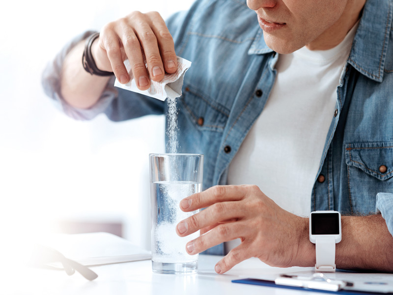 Man mixing sachet into a glass of water