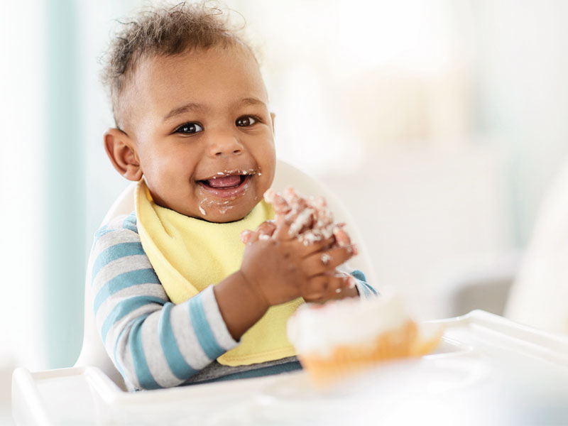 Infant with food on hand and mouth