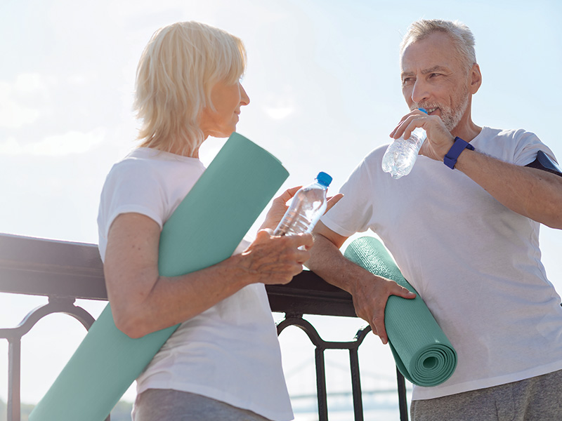 Healthy agers holding yoga mats