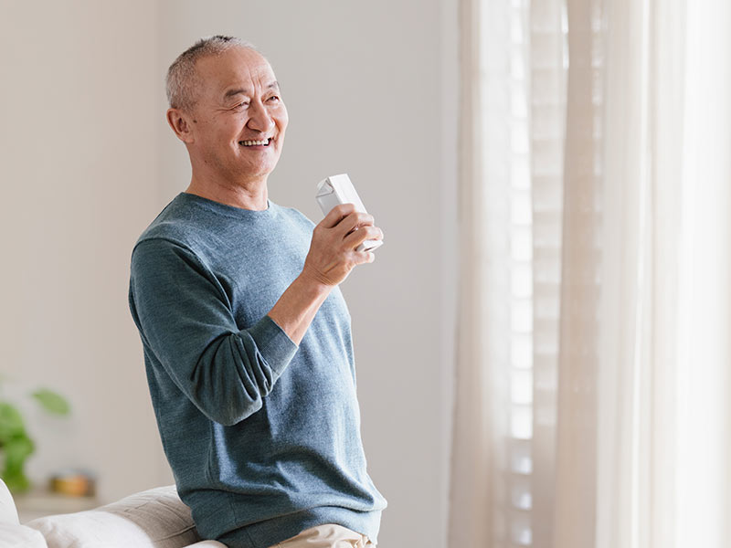 Elderly man holding medical beverage