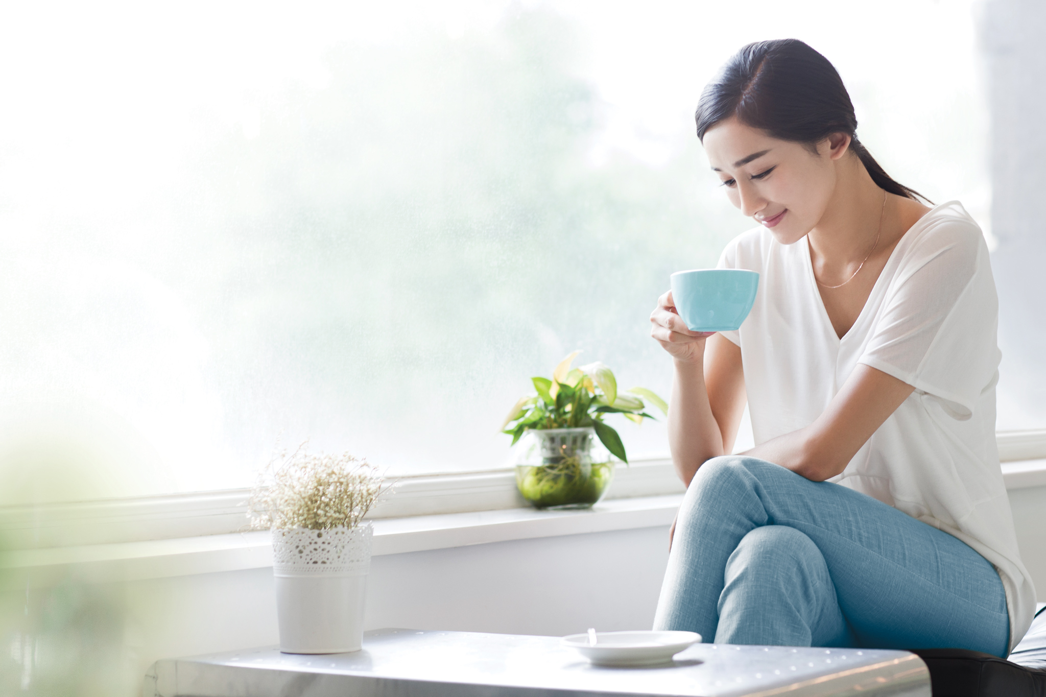 Chinese female sitting at cafe enjoying hot drink